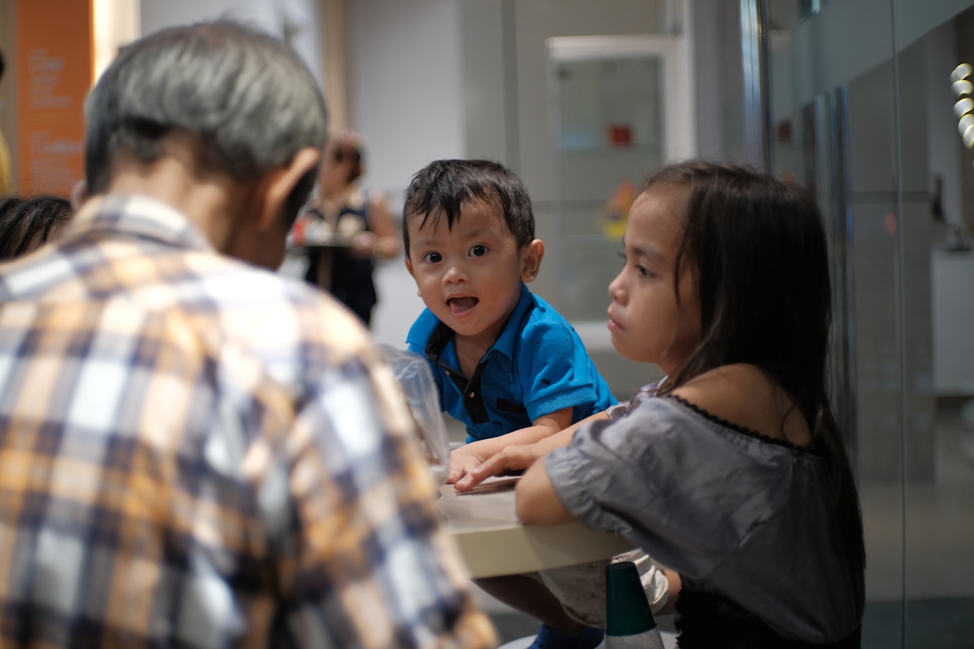 Two children working at a table with an adult