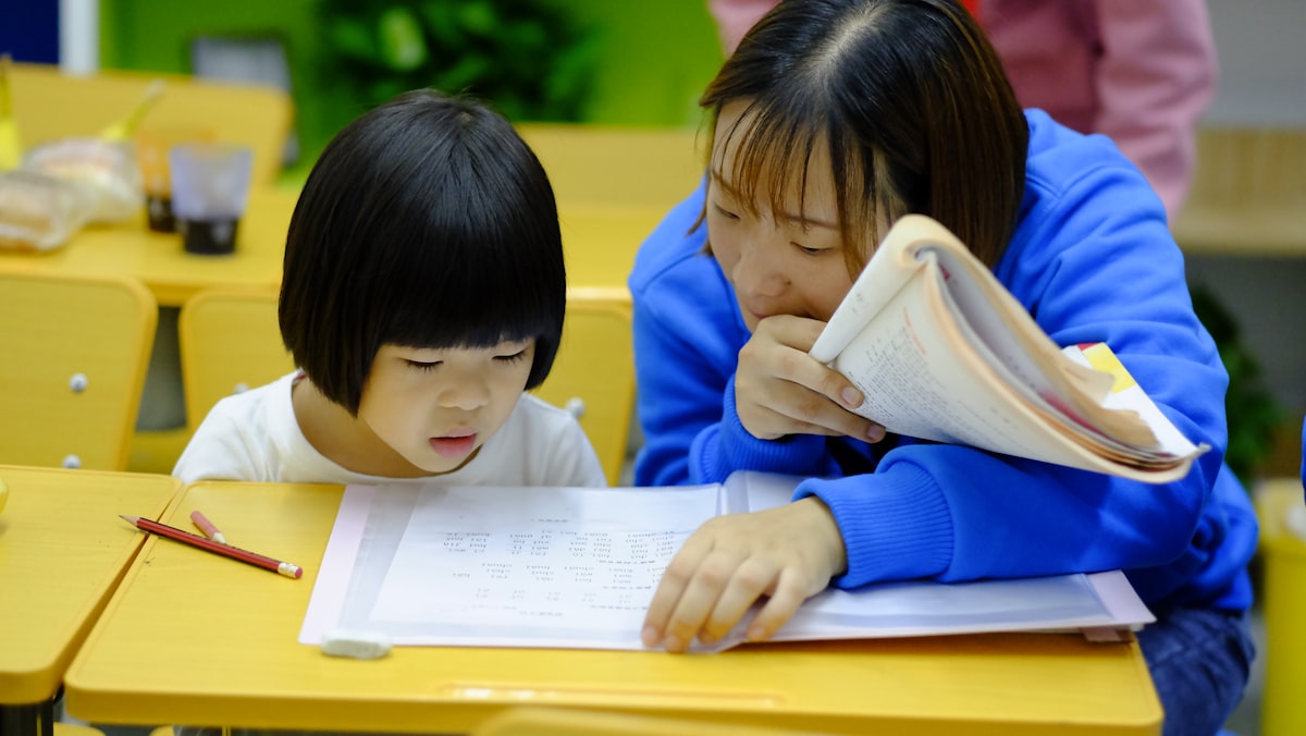 A teacher working one-to-one with a young girl at a desk